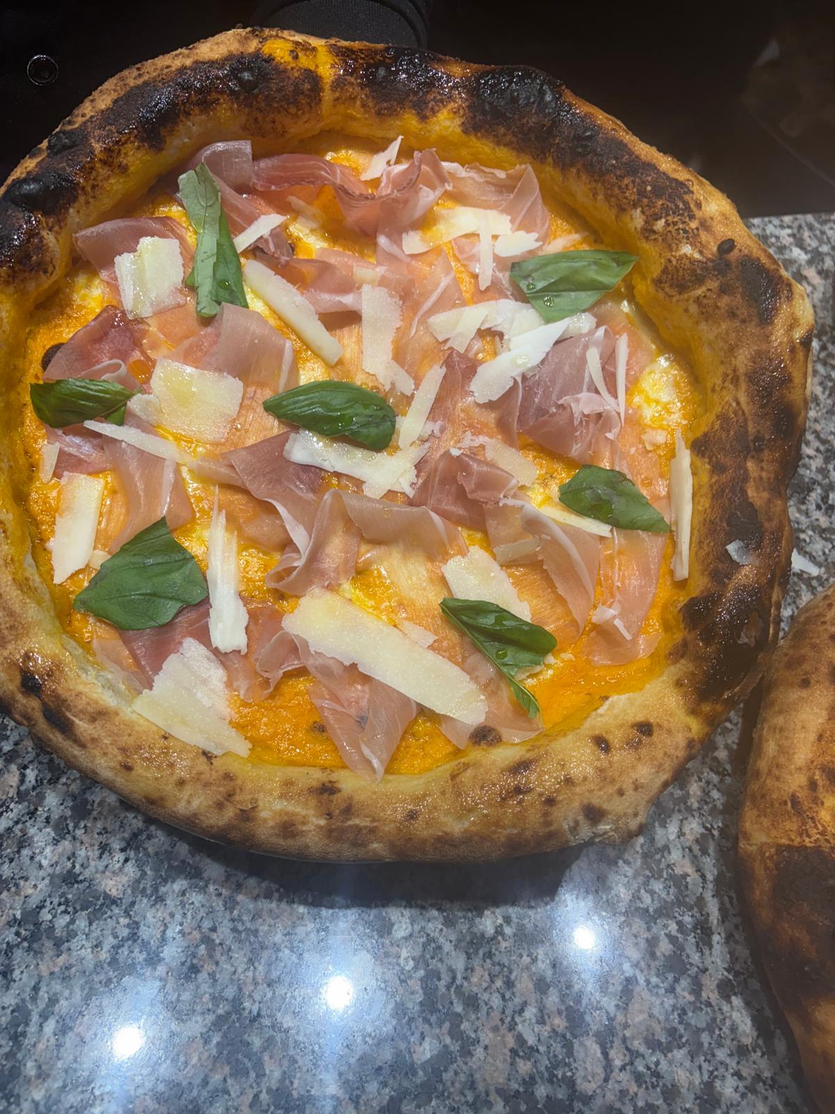 Pizza con prosciutto crudo, scaglie di formaggio e basilico
